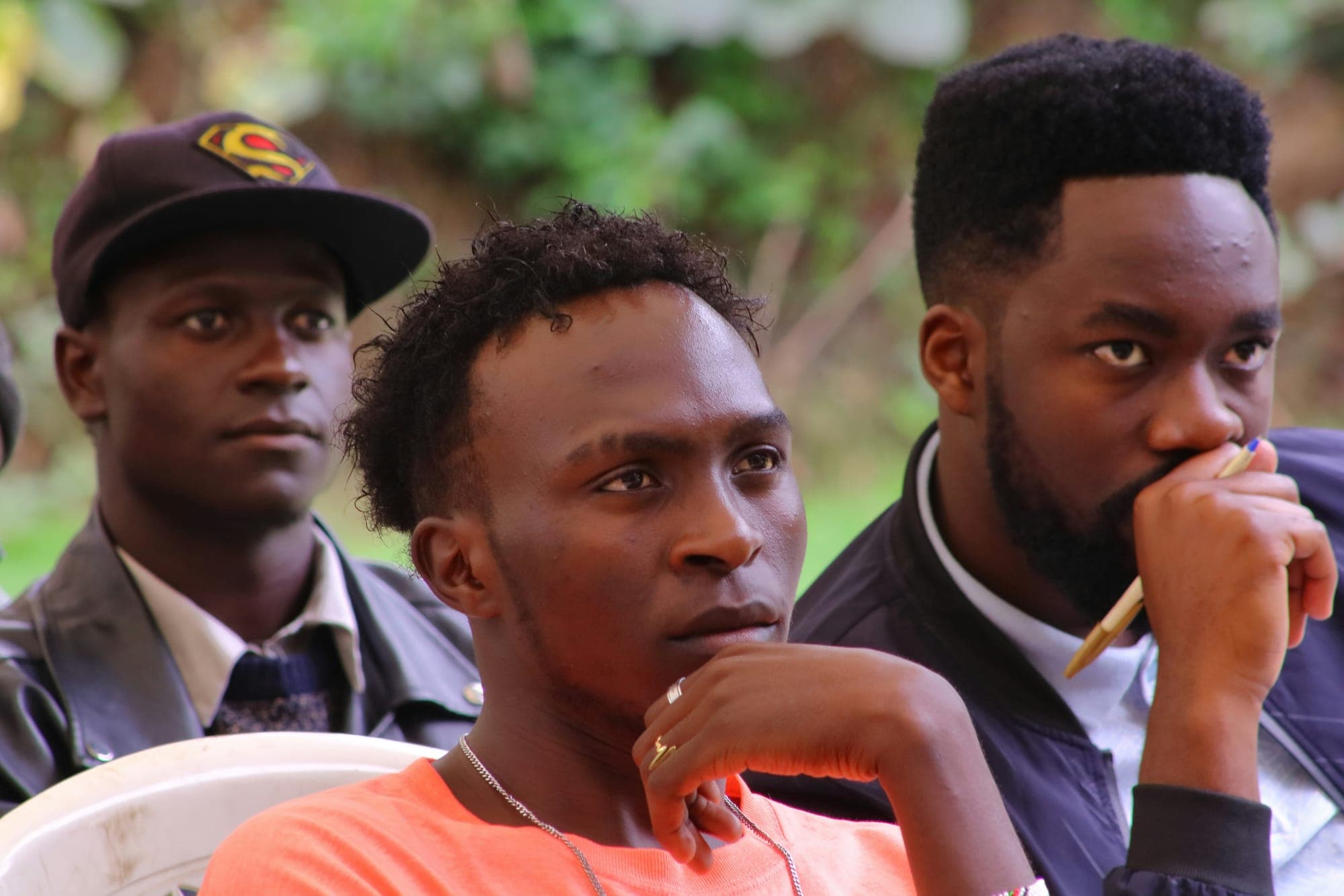 Three young men listening intently during a community discussion