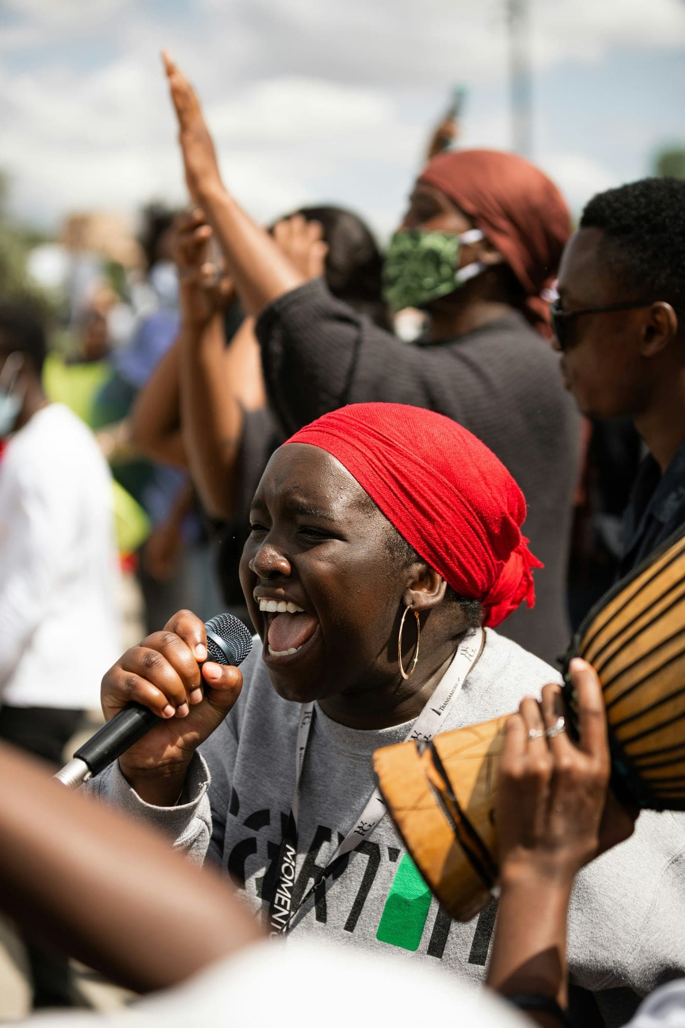A woman speaking passionately into a microphone at a rally, fists raised behind her